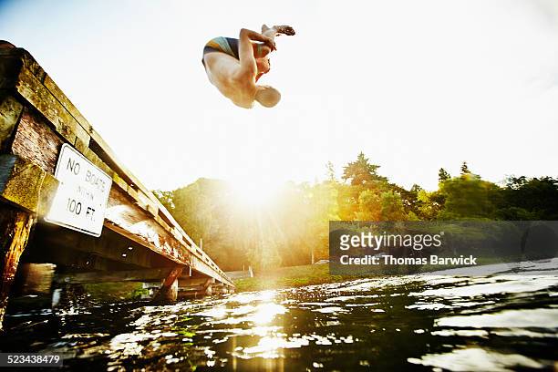 man doing a backflip off of wooden dock into lake - seattle pier stock pictures, royalty-free photos & images