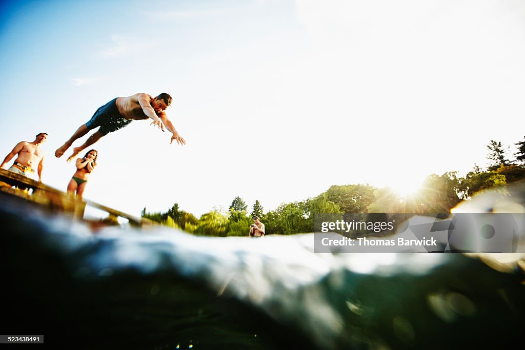 Man diving from wooden dock into lake