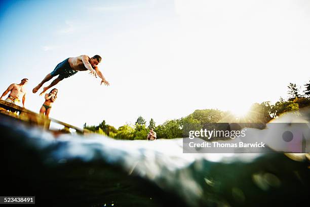 man diving from wooden dock into lake - group-of-friends-jumping-off-dock-into-lake stock pictures, royalty-free photos & images