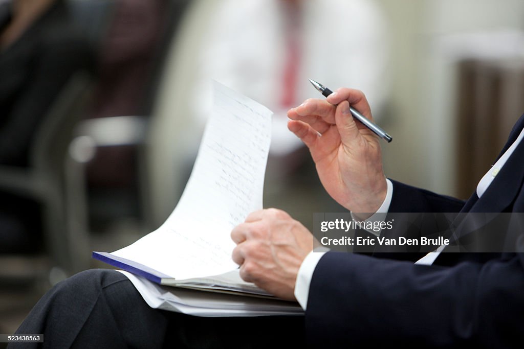 Man's hand holding a pen holding a note pad on his