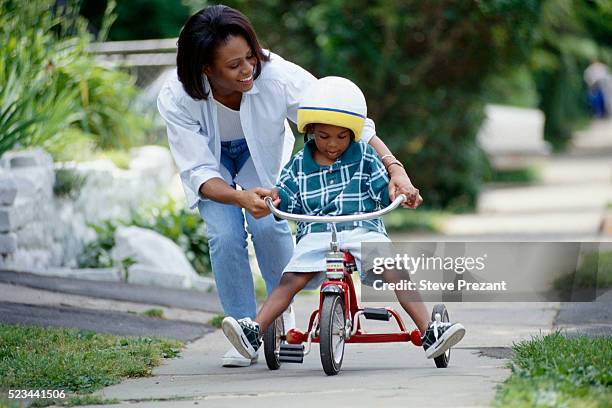 mother teaching son to ride his tricycle - tricycle stock pictures, royalty-free photos & images