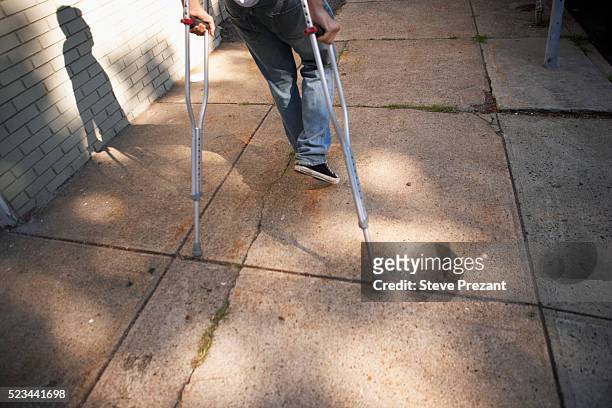 man walking with crutches - crutch stock pictures, royalty-free photos & images