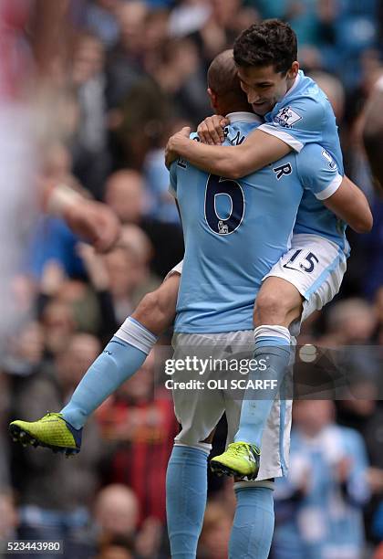 Manchester City's Spanish midfielder Jesus Navas jumps into the arms of Manchester City's Brazilian midfielder Fernando after Fernando scores the...