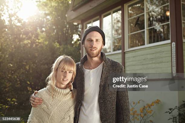 portrait of a young couple standing infront of a house - rural couple young stockfoto's en -beelden