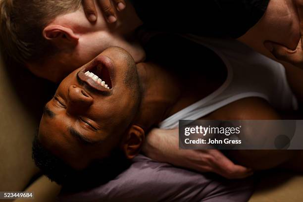 gay men kissing on sofa - interracial kissing stock pictures, royalty-free photos & images