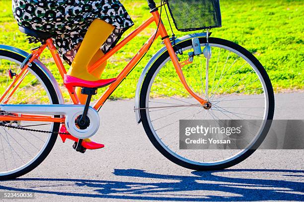 woman riding a bicycle - orange high heels stock-fotos und bilder