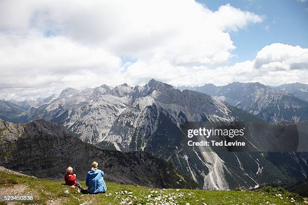 woman with son (4-5) sitting in the grass, watching mountain landscape - allgau stock pictures, royalty-free photos & images