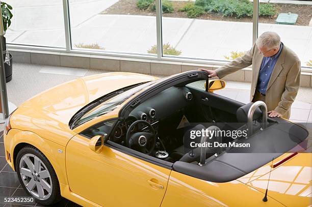 middle-aged man looking at yellow sports car - convertible stock pictures, royalty-free photos & images