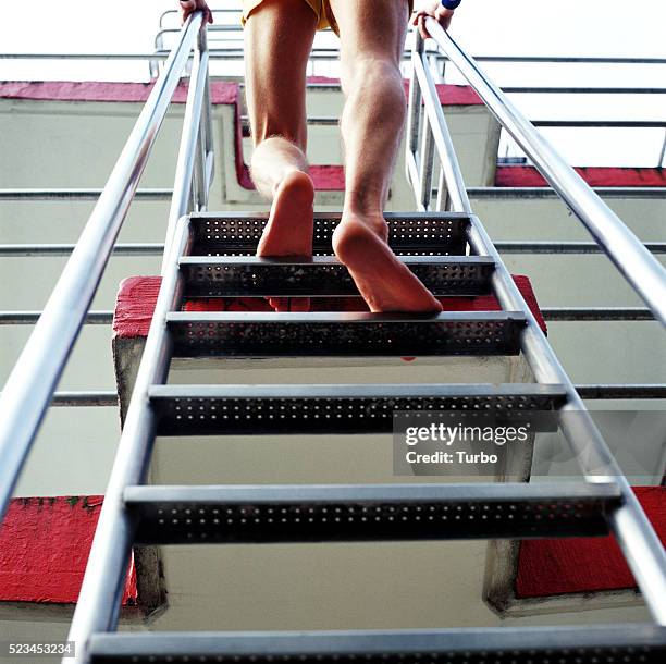 man going up on diving platforms - diving platform pool stock pictures, royalty-free photos & images
