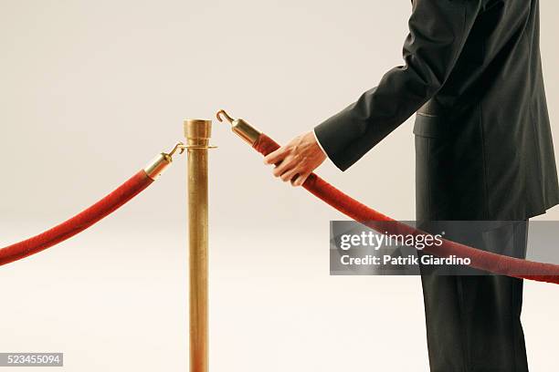 man holding velvet rope - seilabsperrung stock-fotos und bilder