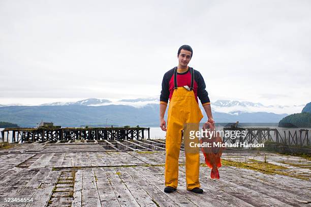 young fisherman holding large red fish on wooden dock - pêcheur photos et images de collection