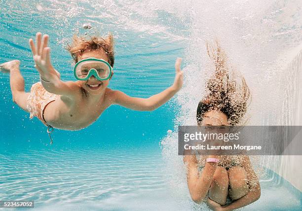 girl and boy underwater in swimming pool - onder water stockfoto's en -beelden