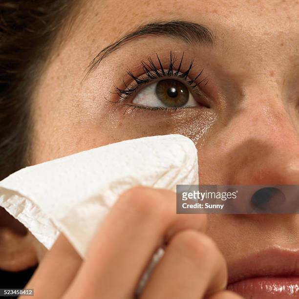young woman wiping away tears - teardrop imagens e fotografias de stock