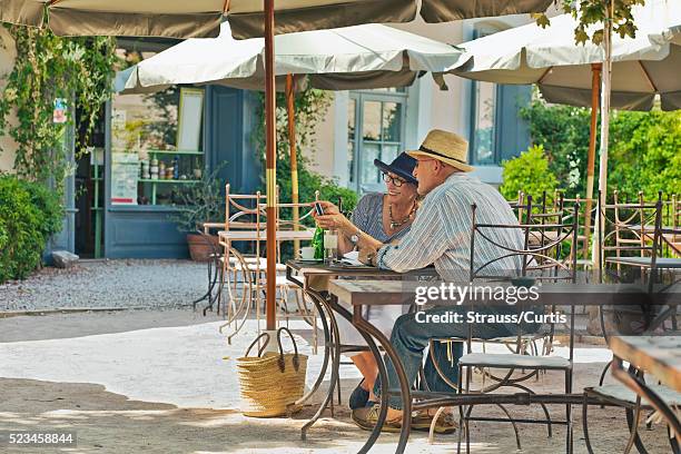 couple sharing photos on digital camera in outdoor cafe. - frans terras stockfoto's en -beelden