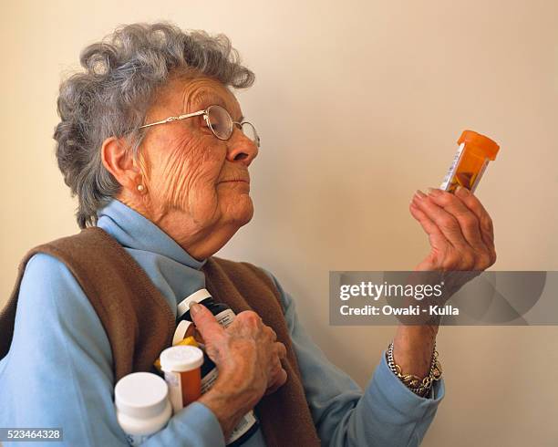 elderly woman reading prescription bottle - prescription label stock pictures, royalty-free photos & images