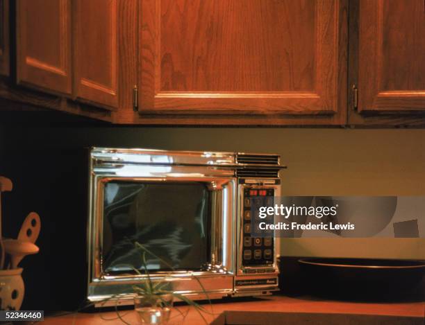 Chrome Radarange by Amana microwave oven features a keypad and digital display screen and sits on a kitchen countertop, 1970s.