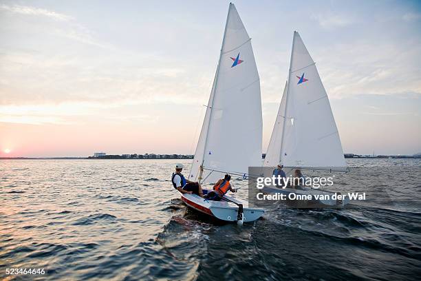 two vanguard 15 sailboats in a friendly sunset race - velista foto e immagini stock