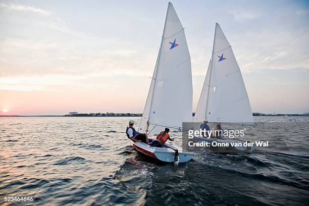 two vanguard 15 sailboats in a friendly sunset race - sail stock pictures, royalty-free photos & images
