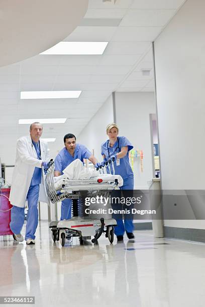 doctor and nurses pushing woman on gurney - stretcher photos et images de collection