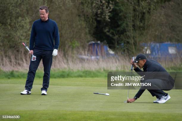 President Barack Obama lines up a putt as British Prime Minister David Cameron looks on from the 3rd green at The Grove Golf Course near Watford in...