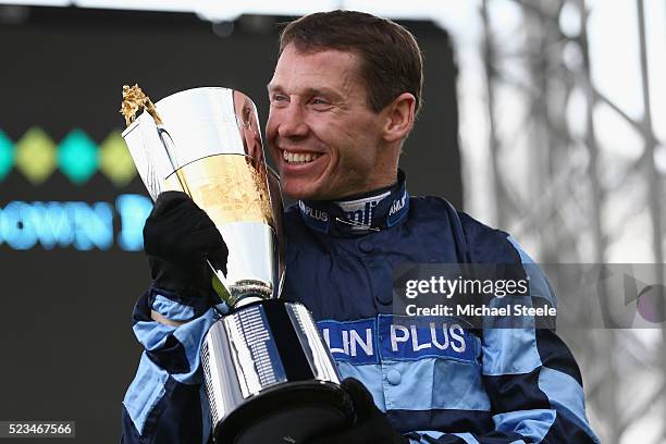 Richard Johnson receives the champion jockey trophy from Sir Anthony McCoy at Sandown Park on April 23, 2016 in Esher, England.