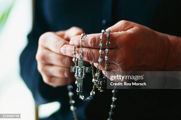 praying with rosary beads - rosary beads stock pictures, royalty-free photos & images