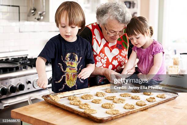 grandma and grandchildren (3 yrs+2yrs) baking - grandmother and grandchild stockfoto's en -beelden