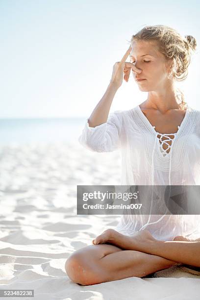 woman practices pranayama in lotus pose on the beach - pranayama stock pictures, royalty-free photos & images