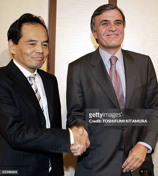 Philippe Jarry, Director General of Carrefour Asia shakes hands with Japan's largest retailer Aeon President Motoya Okada after their joint press...