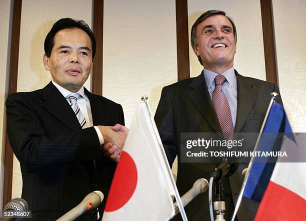 Philippe Jarry, Director General of Carrefour Asia shakes hands with Japan's largest retailer Aeon President Motoya Okada after their joint press...