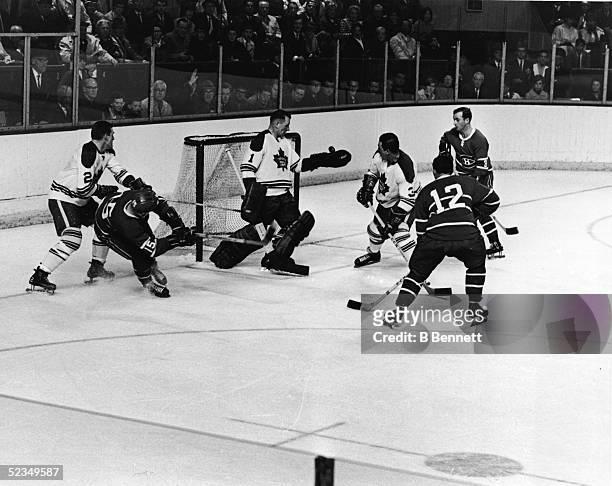 Goalie Johnny Bower of the Toronto Maple Leafs, juggles the puck in his glove following a shot by Bobby Rousseau of the Montreal Canadiens during a...