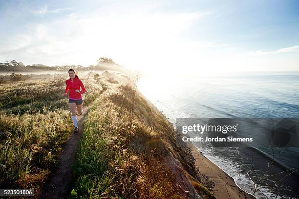 young woman trail running near coast - santa barbara foto e immagini stock