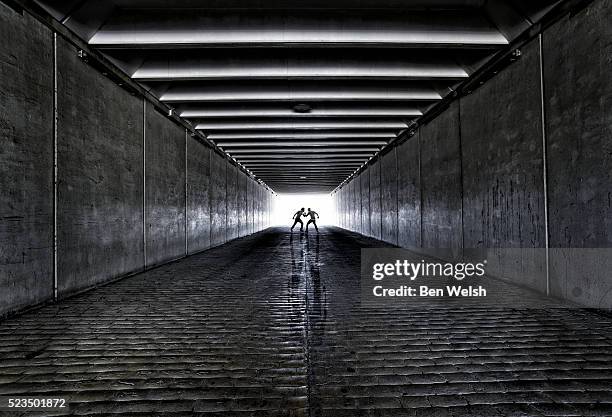 men fighting in a tunnel - onheilspellend stockfoto's en -beelden