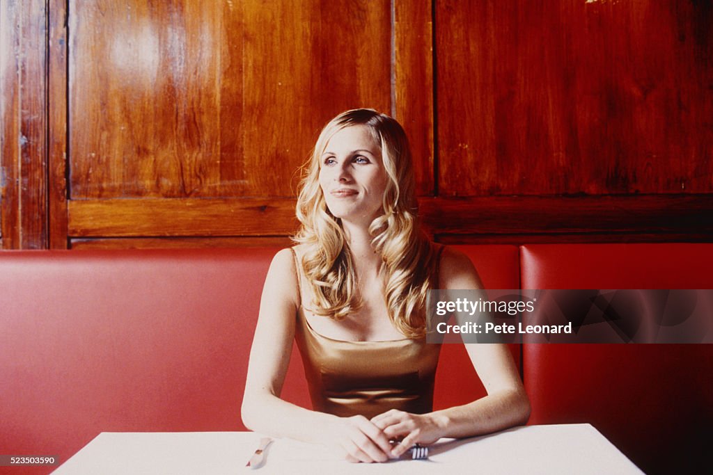 Young Woman Sitting on Red Sofa in Restaurant