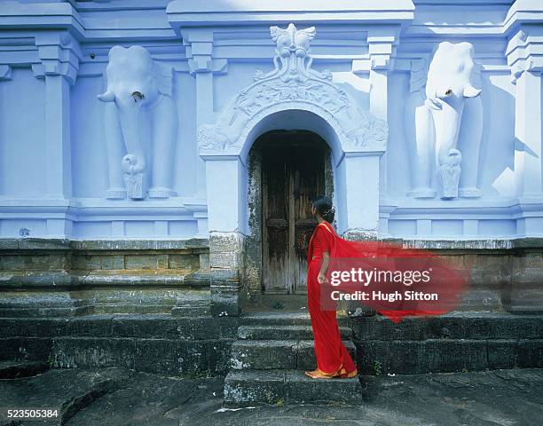 woman in red clothes in front of temple, sri lanka - hugh sitton india fotografías e imágenes de stock