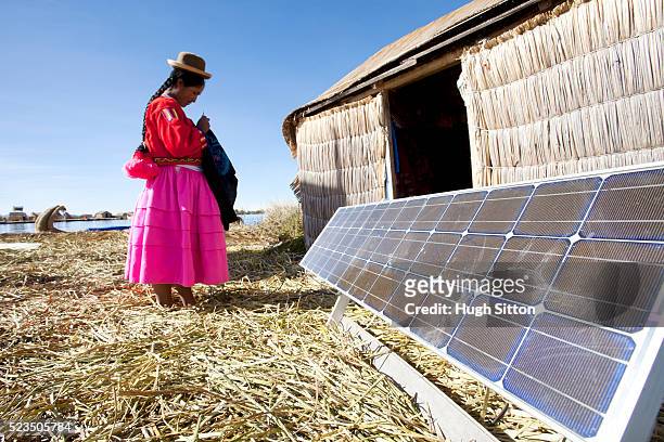 peruvian woman of the uros islands, lake titicaca, with solar panel. puno, peru. - zonne eiland stockfoto's en -beelden