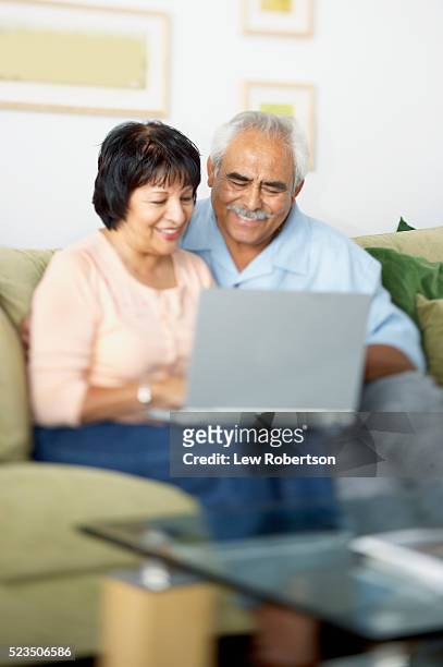 couple on sofa using laptop - couple 50 55 laptop stock-fotos und bilder
