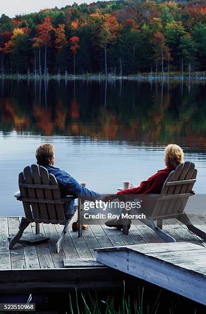 couple enjoying a tranquil lake - adirondack chair stock pictures, royalty-free photos & images