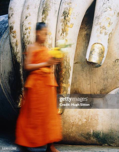 girl holding bouquet by giant buddha statue - wat si chum stockfoto's en -beelden