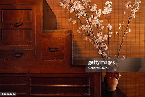 vase of cherry blossoms on wooden chest - bureau vintage stock-fotos und bilder