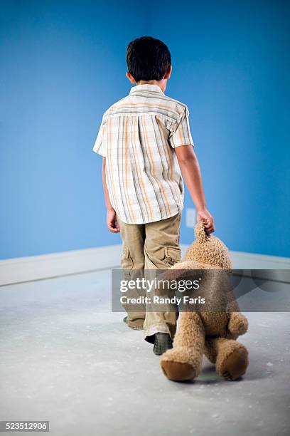 boy dragging teddy bear into time-out corner - traîner photos et images de collection