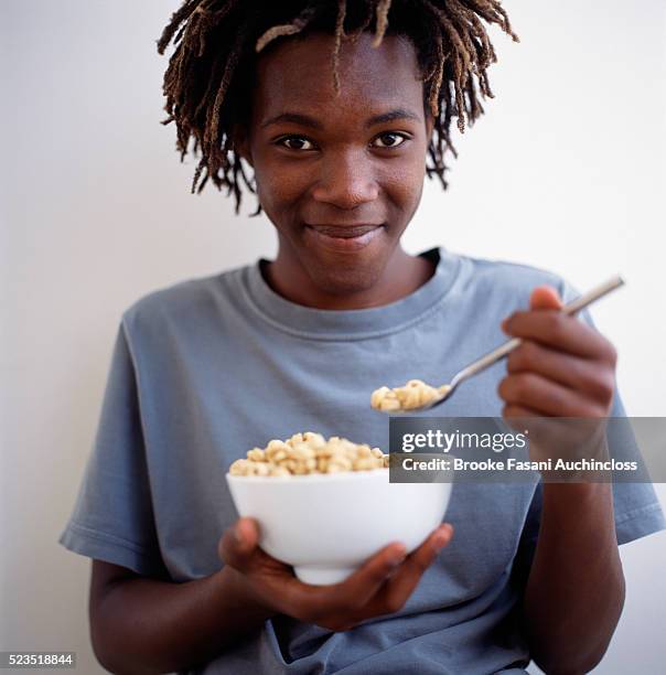 teenager with bowl of cereal - boy eating cereal foto e immagini stock