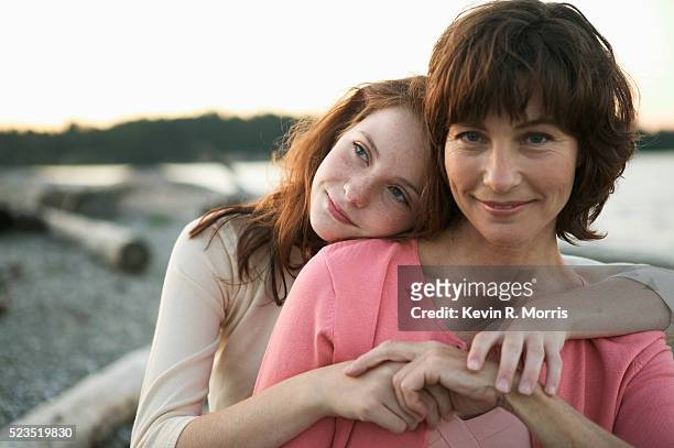 mother and daughter on beach at dusk - two parents photos et images de collection