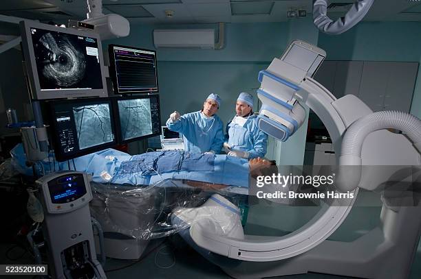 doctors reviewing patient tests in a cardiac catheterization laboratory - patient healthcare technology stock-fotos und bilder