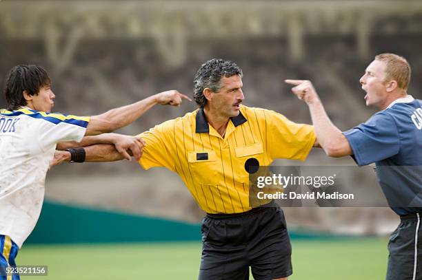 referee separating arguing soccer players - referee fotografías e imágenes de stock