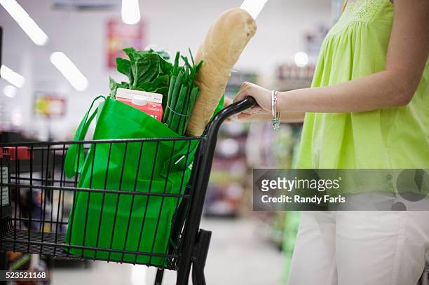 woman pushing grocery car - reusable bag stock pictures, royalty-free photos & images