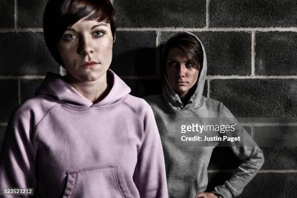 two intimidating teenage girls in hooded tops - gangster girl stock pictures, royalty-free photos & images