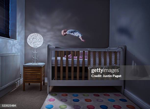 baby (1-6 months) levitating above cot in bedroom - cot imagens e fotografias de stock