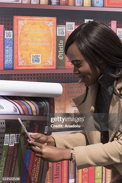 Woman uses iPhone to read QR code for a William Shakespeare book at the Feast of St George marking the 400th anniversary William Shakespeare's death...