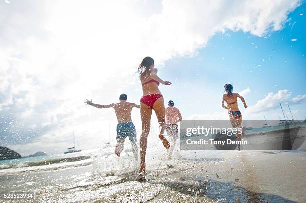 friends running into sea - cane garden bay stock pictures, royalty-free photos & images